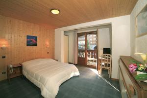 a bedroom with a large bed and a balcony at Hotel Club Blanche Neige in Courchevel