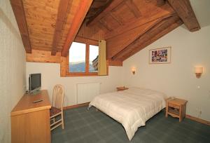 a bedroom with a bed and a desk with a television at Hotel Club Blanche Neige in Courchevel