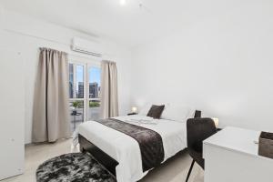 a white bedroom with a bed and a window at Mnasiadou Suite 16 in Nicosia