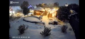 a snow covered yard with a hot tub and a house at Domek u Małysza in Istebna