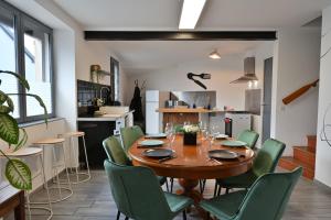 a dining room with a wooden table and green chairs at La Champtocette de la Loire in Champtoceaux +7 photos