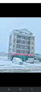 a large building with cars parked in the snow at Paradise Banihal Hotel in Banihāl