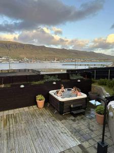two people in a hot tub on a patio at Penthouse by Krambatangi in Øravík