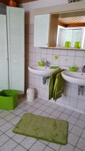 a bathroom with two sinks and a green rug at Gästehaus Baur in Kappel-Grafenhausen