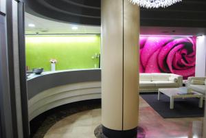 vestíbulo con sofá y pared rosa en Hotel Rio Arga, en Zaragoza