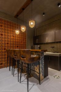 a kitchen with a bar with leather stools and a sink at Sathkara Resort Ella in Ella
