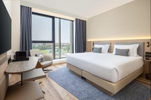 a bedroom with a large bed and a large window at Courtyard by Marriott Milano Linate in Milan