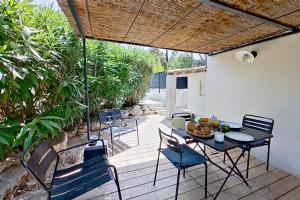 a patio with a table and chairs on a deck at Home Cassis - Maison Les Calanques - Piscine chauffée à 30c in Cassis