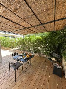 a patio with a table and chairs on a wooden deck at Home Cassis - Maison Les Calanques - Piscine chauffée à 30c in Cassis