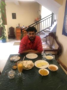 a man sitting at a table with plates of food at MALWATHTHA MOUNT VILLA KANDY in Kandy