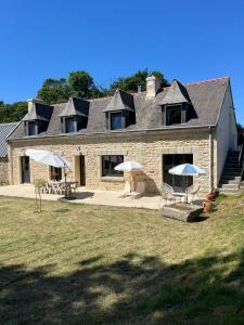 a large stone house with umbrellas in front of it at La longère de Ty Pors in Combrit