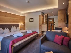 a bedroom with a large bed and a couch at Sporthotel Wagrain in Wagrain +71 photos