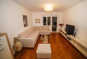 a living room with a white couch and a television at Spacious beach apartment in Razvala
