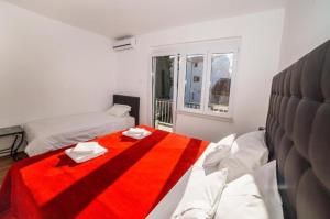 a white room with two beds and a red blanket at Spacious beach apartment in Razvala