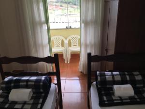 two beds and chairs in a room with a window at Hostel Rotor in Ouro Branco