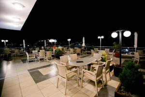 a restaurant with tables and chairs on a balcony at night at Oceanis Hotel in Kavála