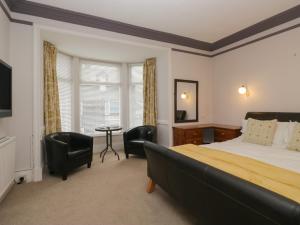 a bedroom with a bed and chairs and a table at Norwood House in Ambleside