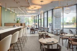a restaurant with tables and chairs and windows at Courtyard by Marriott Milano Linate in Milan