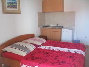 a small bedroom with a bed with a red blanket at Apartmani kod Rade in Pakoštane