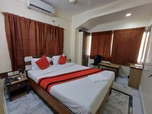 a bedroom with a large bed with red pillows at Welcome Regency in kolkata