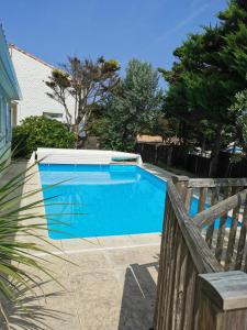 a large blue swimming pool next to a wooden fence at Villa des Oceanides in Saint-Gilles-Croix-de-Vie