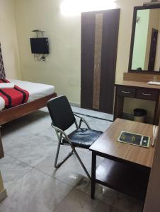 a room with a chair and a desk and a bed at Welcome Regency in kolkata