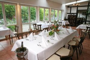 uma sala de jantar com mesas e cadeiras brancas e janelas em Nigel Restaurant & Hotel im Wendland em Bergen an der Dumme