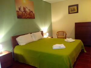 a bedroom with a green bed with two towels on it at Monte Família Ferreira in Vale de Açor