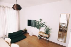 a living room with a green couch and a mirror at Furano Cozy Whole House for 6 - Near lavender farm and Ski Resort - free parking in Nakafurano