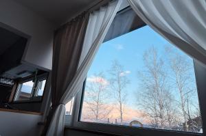 a window in a room with a view of trees at Furano Cozy Whole House for 6 - Near lavender farm and Ski Resort - free parking in Nakafurano