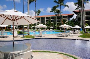 a pool with a table and chairs and umbrellas at Studio Muro Alto in Porto De Galinhas +6 photos
