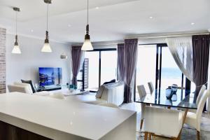 a living room with white furniture and large windows at Foreshore 2 Sea View Holiday accommodation in Langstrand