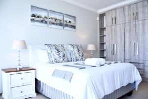 a white bedroom with a bed and a cabinet at Foreshore 2 Sea View Holiday accommodation in Langstrand