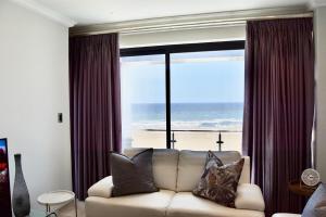 a living room with a couch and a view of the beach at Foreshore 2 Sea View Holiday accommodation in Langstrand