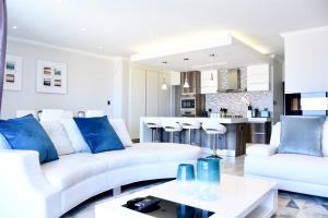 a living room with white furniture and blue pillows at Foreshore 2 Sea View Holiday accommodation in Langstrand