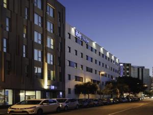 a large building with cars parked in front of it at Ibis Budget Málaga Centro in Málaga
