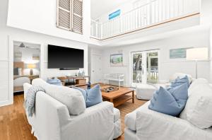 a living room with white furniture and a flat screen tv at Sugar and Spice in Santa Rosa Beach