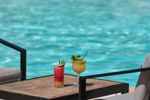 two cocktails sitting on a table next to the water at Pacifae Hotel in Katelios