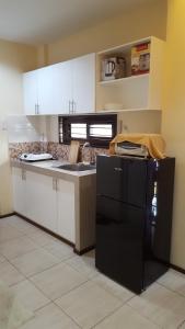 a kitchen with a black refrigerator and white cabinets at Alegre Building Lipa in Lipa