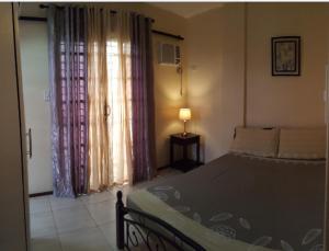 a bedroom with a bed and a lamp and a window at Alegre Building Lipa in Lipa