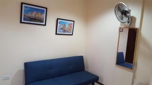 a room with a blue couch and a fan at Alegre Building Lipa in Lipa
