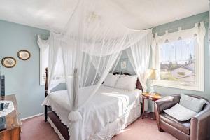 a bedroom with a canopy bed and a chair at Charming Victorian Home in Okotoks Elegant Comfort Modern Convenience in Okotoks
