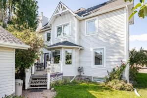 a white house with a porch and a yard at Charming Victorian Home in Okotoks Elegant Comfort Modern Convenience in Okotoks