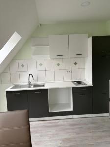 a kitchen with white and black cabinets and a sink at Red Dot Apartment Lucky in Kamen