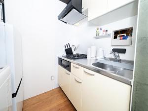 a kitchen with white cabinets and a sink at 旅鴉 inn 高松 - 高松駅徒歩5分 in Takamatsu