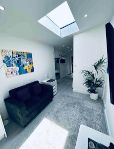 a living room with a black couch and a skylight at Apartment style Space ideal for business & contractors in Minworth