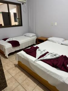 two beds in a room with a mirror at Pousada Refúgio da Ilha in São Mateus