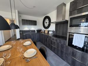 a kitchen with a wooden table with plates and wine glasses at Appartement moderne Senlis in Senlis