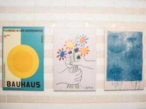 three posters on a wall with a hand holding flowers at 旅鴉 inn 高松 - 高松駅徒歩5分 in Takamatsu +17 photos