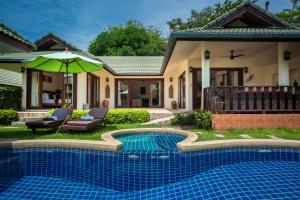 a house with a swimming pool in front of a house at Idyllic Samui Beach Villa Resort in Choeng Mon Beach